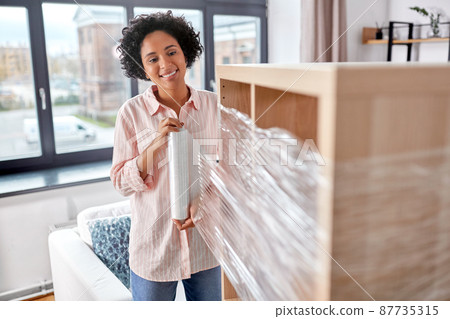 happy woman packing shelf and moving to new home 87735315