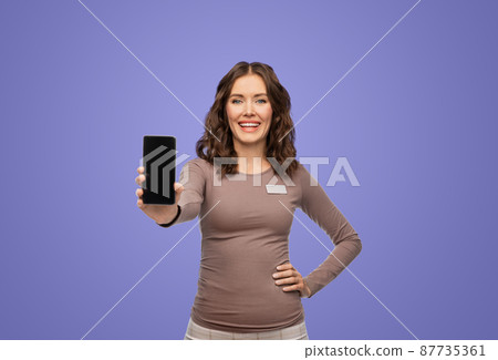 happy female shop assistant showing smartphone happy female shop assistant showing smartphone 87735361