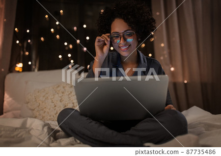 happy woman with laptop working in bed at night happy woman with laptop working in bed at night 87735486