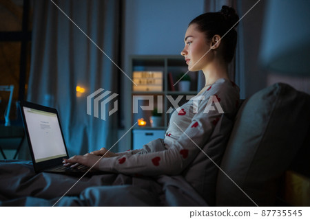 teenage girl with laptop in bed at home at night teenage girl with laptop in bed at home at night 87735545