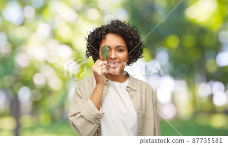 smiling woman holding leaf over green background smiling woman holding leaf over green background 87735581
