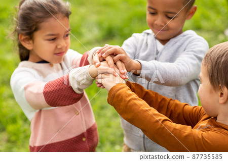 group of children stacking hands at park 87735585