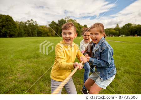 happy children playing tug-of-war game at park 87735606
