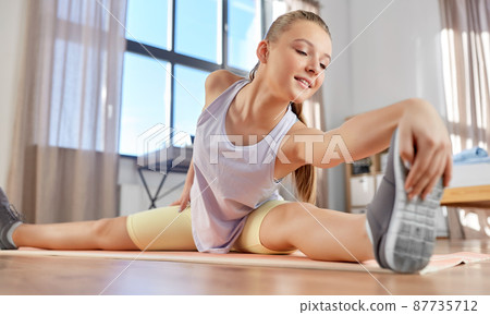 happy teenage girl exercising on yoga mat at home happy teenage girl exercising on yoga mat at home 87735712