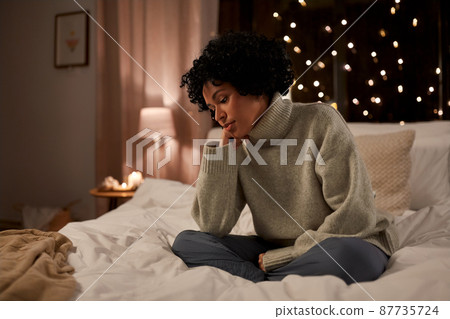 sad woman in sweater on bed at home at night sad woman in sweater on bed at home at night 87735724