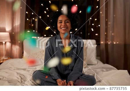 happy woman over confetti in bed at night happy woman over confetti in bed at night 87735735
