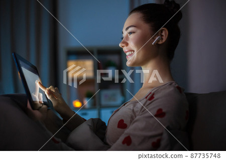 teenage girl with tablet pc and earphones in bed teenage girl with tablet pc and earphones in bed 87735748