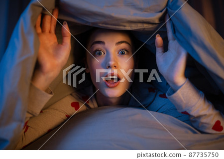 surprised teenage girl under blanket in bed surprised teenage girl under blanket in bed 87735750