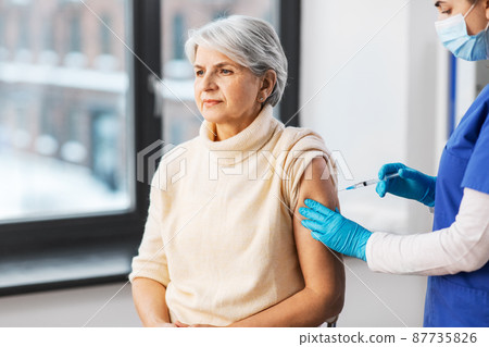 nurse with syringe making injection to woman nurse with syringe making injection to woman 87735826