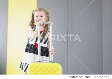 Pretty little girl going on vacation, packed stuff in yellow suitcase, kid in lovely summer dress Pretty little girl going on vacation, packed stuff in yellow suitcase, kid in lovely summer dress 87735835