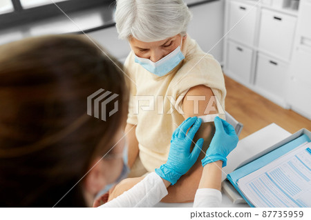 nurse applying medical patch to vaccinated woman 87735959