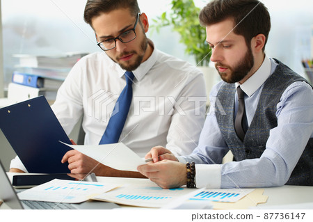 Coworkers men go through financial papers, solve and discuss problems 87736147
