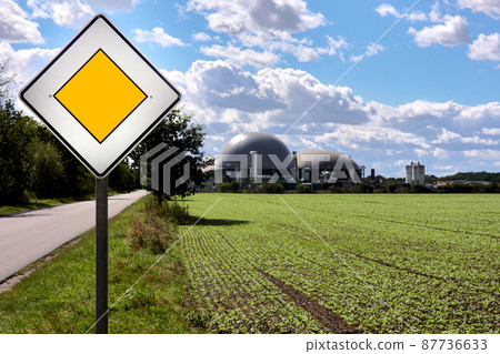 Concept right of way for renewable energy, right of way sign in front of a field and a biogas plant for the production of electricity from garbage 87736633