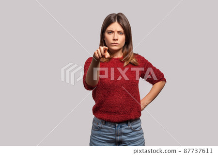 Hey you. Portrait of angry bossy brunette woman in shaggy sweater pointing finger to camera, looking with suspicion and accusing, choosing guilty. indoor studio shot isolated on gray background Hey you. Portrait of angry bossy brunette woman in shaggy sweater pointing finger to camera, looking with suspicion and accusing, choosing guilty. indoor studio shot isolated on gray background 87737611