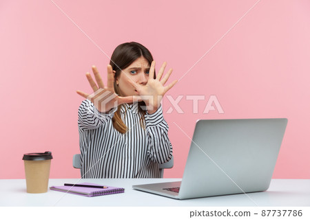 No, I'm scared. Frightened woman with shocked expression raising hands in stop gesture, defending herself, freaked out of troubles working on laptop. Indoor studio shot isolated on pink background No, I'm scared. Frightened woman with shocked expression raising hands in stop gesture, defending herself, freaked out of troubles working on laptop. Indoor studio shot isolated on pink background 87737786