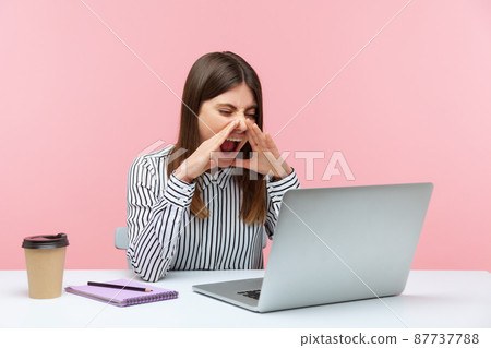 Nervous angry business woman in striped shirt loudly screaming holding hands near mouth, talking video conference sitting at workplace. Indoor studio shot isolated on pink background Nervous angry business woman in striped shirt loudly screaming holding hands near mouth, talking video conference sitting at workplace. Indoor studio shot isolated on pink background 87737788