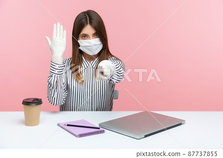 You need protection against coronavirus infection. Woman office employee sitting at workplace wearing hygienic face mask and showing hands in protective gloves, pointing to camera. Covid-19 quarantine You need protection against coronavirus infection. Woman office employee sitting at workplace wearing hygienic face mask and showing hands in protective gloves, pointing to camera. Covid-19 quarantine 87737855
