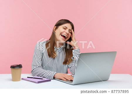 Amused happy woman office worker laughing out loud, sitting at workplace, enjoying funny joke on laptop, having break at home office. Indoor studio shot isolated on pink background Amused happy woman office worker laughing out loud, sitting at workplace, enjoying funny joke on laptop, having break at home office. Indoor studio shot isolated on pink background 87737895
