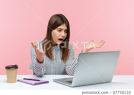 How could you. Irritated woman office worker raising hands in indignant gesture, asking why and looking at laptop screen, talking on video call. Indoor studio shot isolated on pink background 87738110