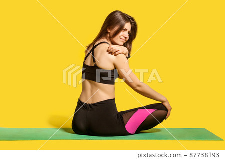 Displeased fitness unhealthy woman feeling pain in shoulder and massaging sore spine, suffering back ache after exercising, sports injury concept. indoor studio shot isolated on yellow background 87738193