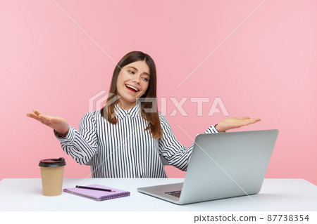 Kind open hearted woman office worker sitting at workplace looking at laptop screen on video call with raised arms, wants to hug or share something. Indoor studio shot isolated on pink background 87738354