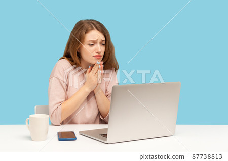 Please, begging for help. Young woman employee holding hands in praying gesture and talking on video call on laptop, asking heartily, pleading with desperate face. indoor studio shot, blue background Please, begging for help. Young woman employee holding hands in praying gesture and talking on video call on laptop, asking heartily, pleading with desperate face. indoor studio shot, blue background 87738813