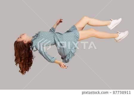 Floating in air. Relaxed girl in vintage ruffle dress levitating keeping eyes closed, sleeping while flying mid-air, having comfortable peaceful dream. full length studio shot isolated on gray, indoor 87738911
