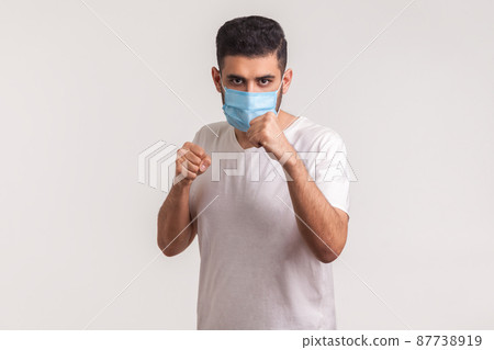 Man in surgical mask punching boxing to camera, fighting against contagious disease, coronavirus infection, respiratory illness such as flu, 2019-nCoV, ebola. studio shot isolated on white background Man in surgical mask punching boxing to camera, fighting against contagious disease, coronavirus infection, respiratory illness such as flu, 2019-nCoV, ebola. studio shot isolated on white background 87738919