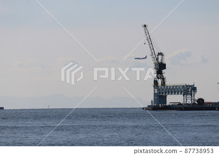 蔚藍的大海,有起重機的港口,朦朧的山,飛機,雲彩和藍天 蔚藍的大海,有起重機的港口,朦朧的山,飛機,雲彩和藍天 87738953