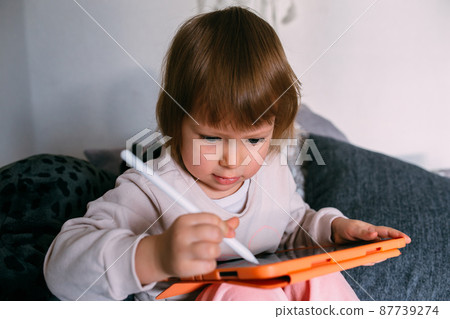 Child using technology. Toddler at home with a tablet and a pen stylus and draws 87739274