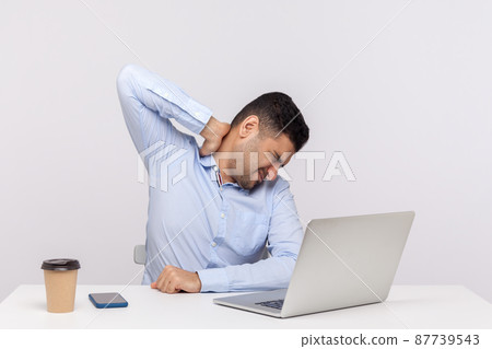 Tired male employee sitting office workplace, touching sore back neck, massaging hurting shoulders, painful stiff muscles, feeling exhausted fatigued. indoor studio shot isolated on white background 87739543
