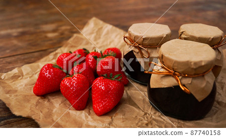 Strawberry jam in the glass jar with fresh berries on wooden background 87740158