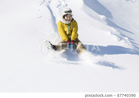 A young woman enjoying sledging in the snowy mountains 87740390