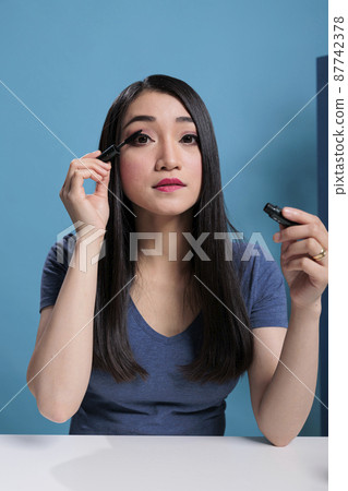 Portrait of asian influencer doing her makeup in front of camera Portrait of asian influencer doing her makeup in front of camera 87742378