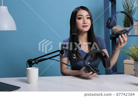 Podcast creator presenting professional headphones in front of camera Podcast creator presenting professional headphones in front of camera 87742384
