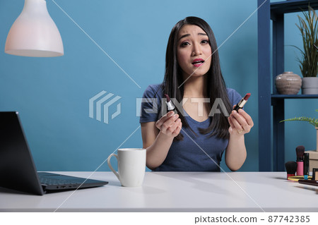 Asian social media influencer holding lipstick talking with remote subscribes Asian social media influencer holding lipstick talking with remote subscribes 87742385