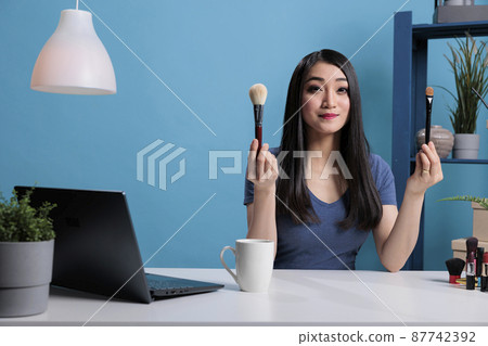 Beauty guru influencer holding make up brushes showing at camera Beauty guru influencer holding make up brushes showing at camera 87742392