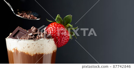 Chocolate drink with whipped cream, strawberry and pieces of black chocolate. 87742846