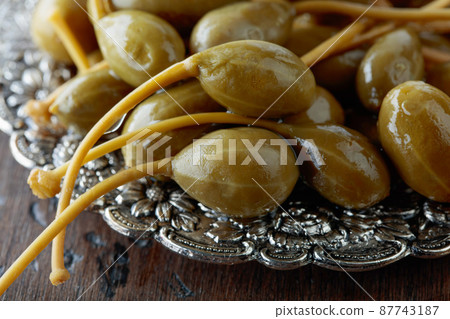 Pickled caper berries in metal dish . 87743187
