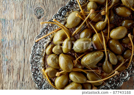 Pickled caper berries in metal dish . 87743188