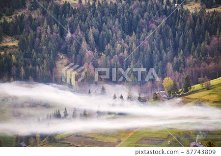 Beautiful spring landscape. Traditional mountain village on hills. Rural Ukraine Carpathian sunrise. Smoke from house. Clouds of fog 87743809