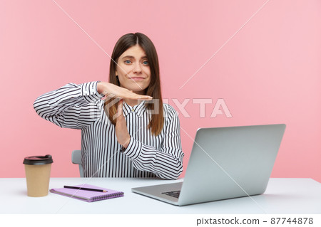Exhausted overworked woman showing time out gesture, asking for break sitting at workplace with laptop, professional burnout. Indoor studio shot isolated on pink background Exhausted overworked woman showing time out gesture, asking for break sitting at workplace with laptop, professional burnout. Indoor studio shot isolated on pink background 87744878