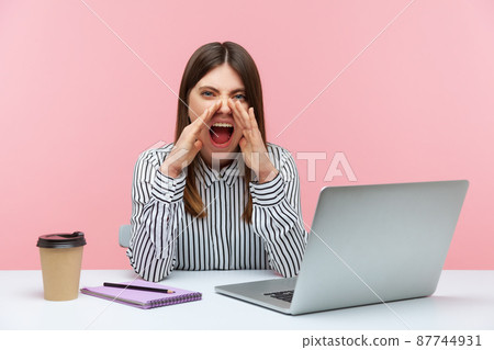 Tired nervous woman office worker loudly yelling looking at camera, sitting at workplace with laptop furious about extra work, difficult job task. Indoor studio shot isolated on pink background Tired nervous woman office worker loudly yelling looking at camera, sitting at workplace with laptop furious about extra work, difficult job task. Indoor studio shot isolated on pink background 87744931