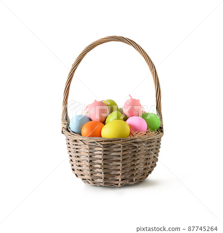 Easter wicker basket with pastel colorful eggs on white. 87745264
