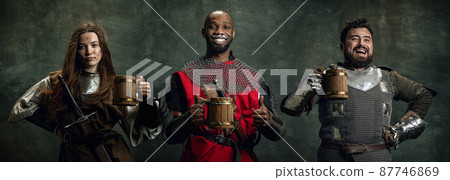 Creative collage with happy men and woman in image of medieval warriors holding big mugs of frothty beer, ale isolated over dark vintage background. Creative collage with happy men and woman in image of medieval warriors holding big mugs of frothty beer, ale isolated over dark vintage background. 87746869