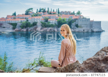 Woman tourist on background of beautiful view of the island of St. Stephen, Sveti Stefan on the Budva Riviera, Budva, Montenegro. Travel to Montenegro concept 87747115