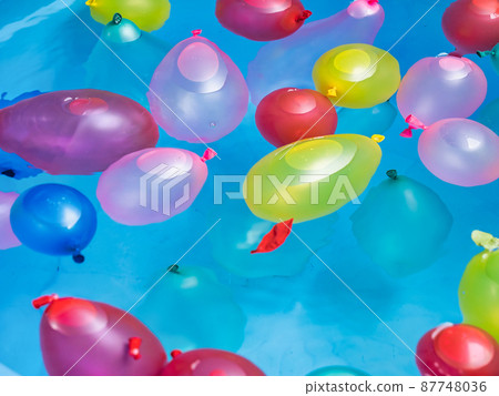 Colorful water balloons floating in a water bucket 87748036