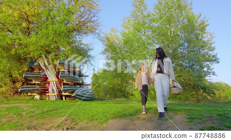 A happy family. Mom and daughter are walking in the forest park. Happy family concept. Mom and daughter are walking hand in hand in the forest park. 87748886
