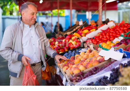 Middle aged man buying peaches Middle aged man buying peaches 87750580