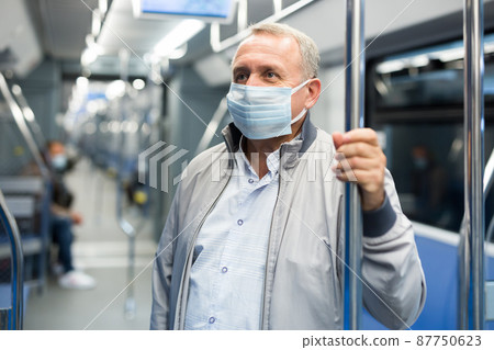 Middle aged man in face mask in subway car Middle aged man in face mask in subway car 87750623